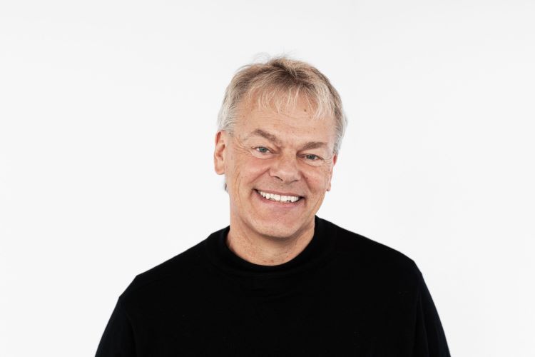 Prof Evard Moser, Head and shoulders photo of white man with grey hair smiling at the camera wearing a black top.